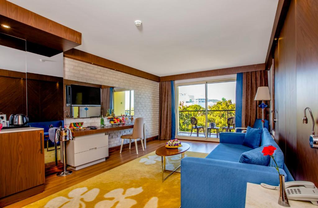 a living room with a blue couch and a kitchen at Sherwood Exclusive Kemer - Kids Concept in Kemer