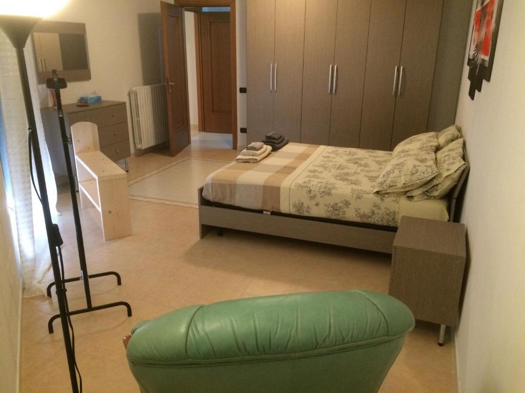 ein Schlafzimmer mit einem Bett und einem grünen Stuhl in der Unterkunft B&B Camelie in Melfi