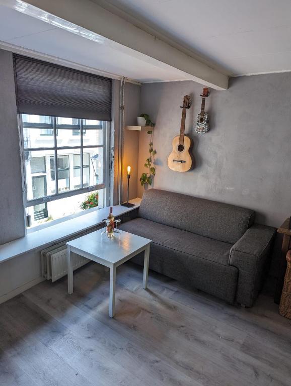 uma sala de estar com um sofá, uma mesa e uma guitarra em Monumental gem in the heart of Utrecht City em Utrecht