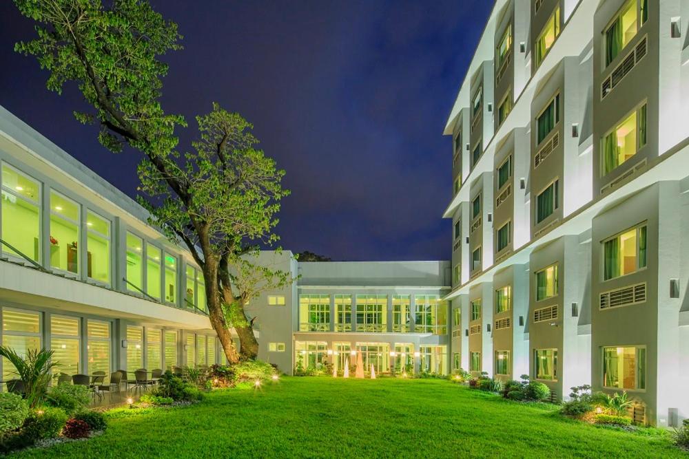 un gran edificio con un césped verde delante de él en Microtel by Wyndham UP Technohub, en Manila