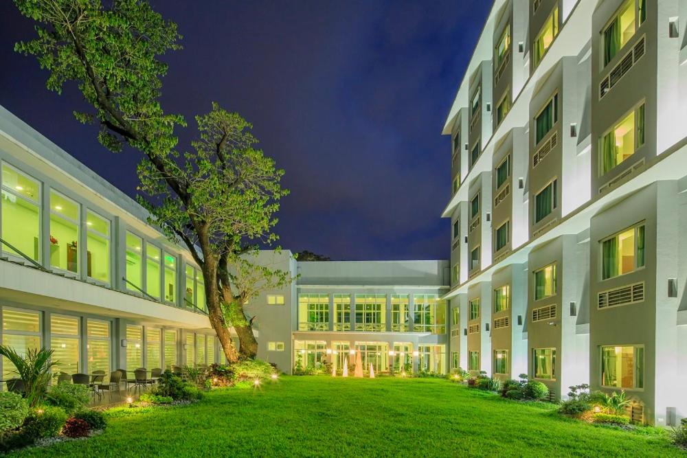 un gran edificio con un césped verde delante de él en Microtel by Wyndham UP Technohub en Manila