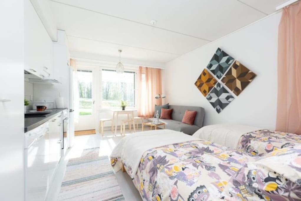a white room with two beds and a kitchen at Cosy studio apartment + free private parking in Kangasala