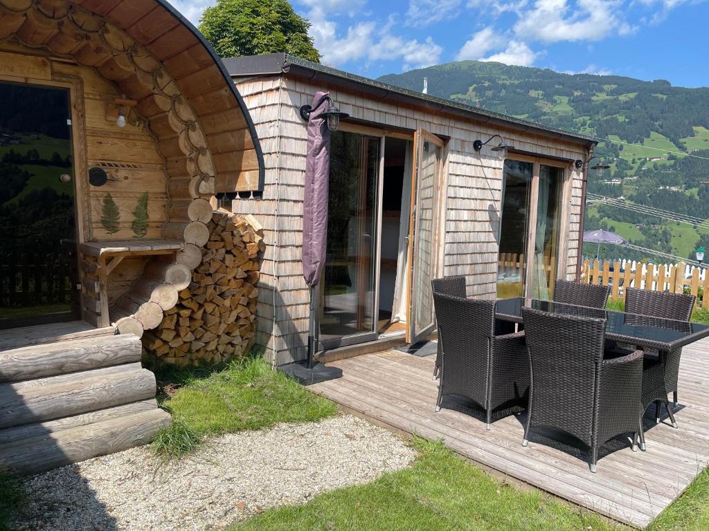 a cabin with a table and chairs on a deck at Chaleny - Das erste Tiny House Chalet im Zillertal in Hainzenberg