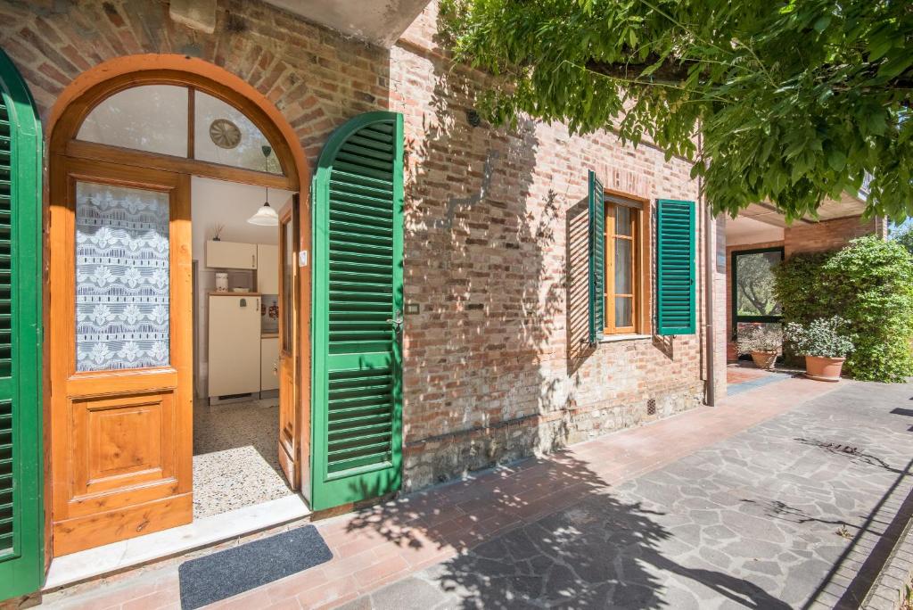 ein Backsteingebäude mit grünen Rollläden und einer Tür in der Unterkunft Podere San Lorenzo in Siena