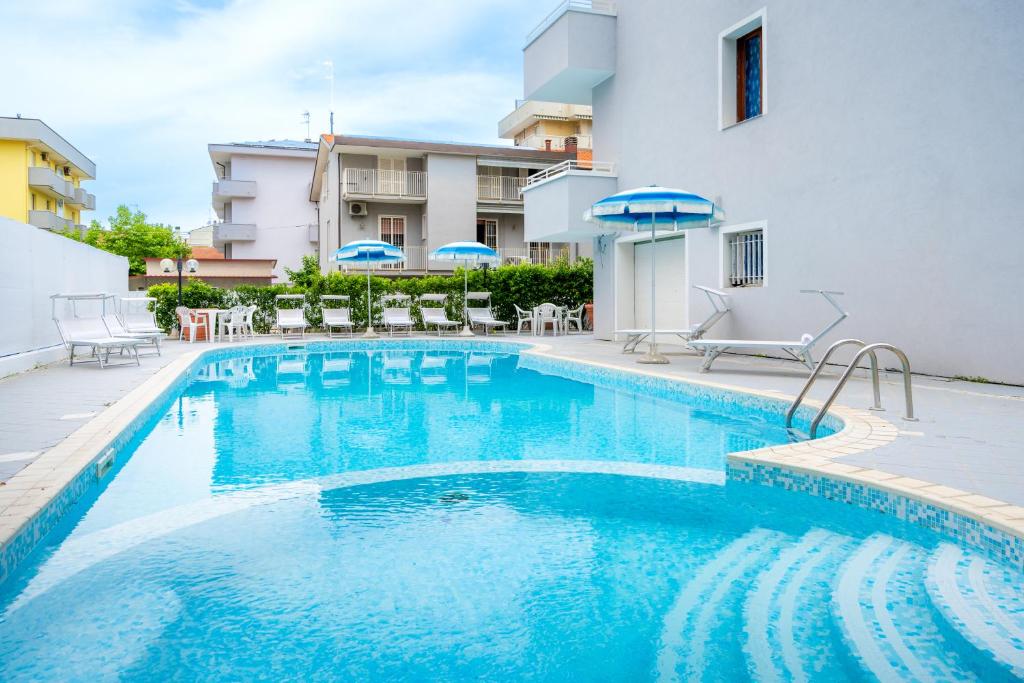 una piscina con sillas y sombrillas junto a un edificio en Appartamenti Feel Good en Rímini