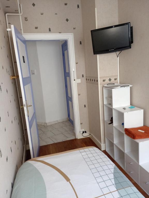 une chambre avec un lit et une télévision à écran plat dans l'établissement Petite chambre meublée au cœur de ville - chez l'habitant, au Creusot