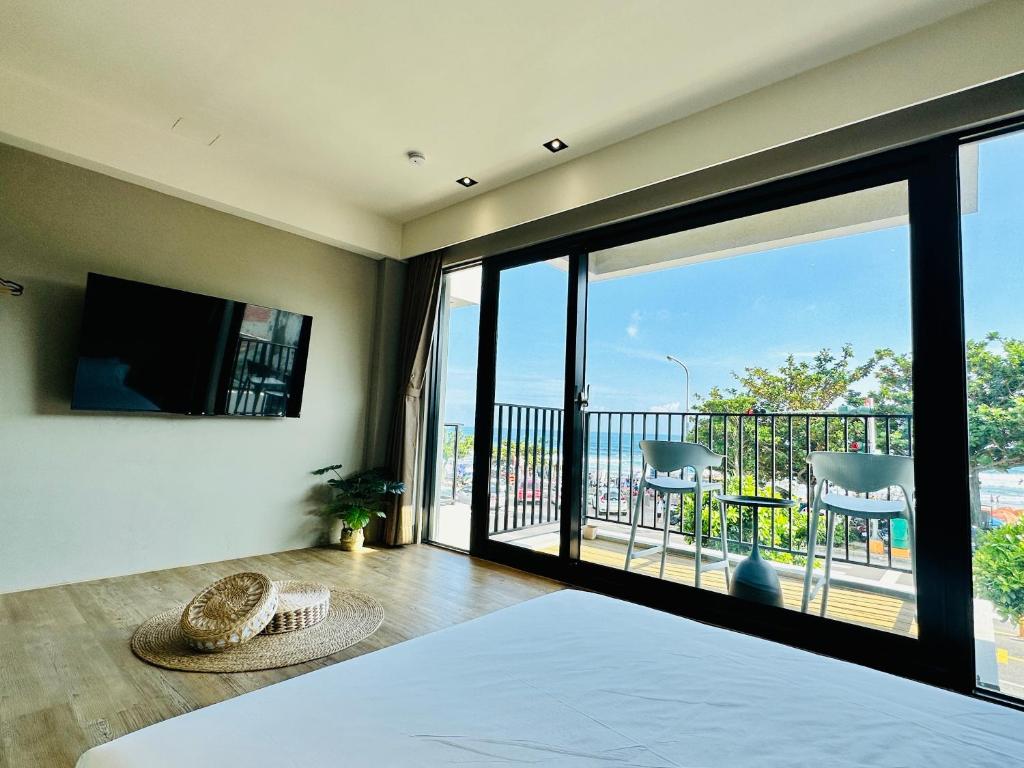 a bedroom with a bed and a view of a balcony at 厝True Hub旅店 in Nanwan