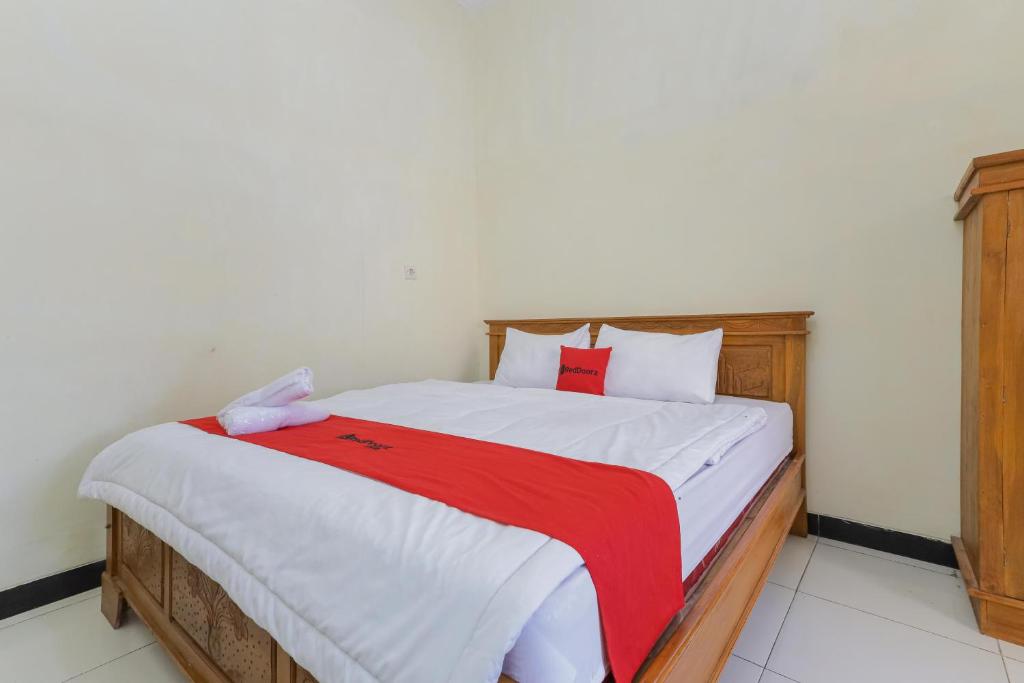 um quarto com uma cama grande e um cobertor vermelho em RedDoorz Syariah near Alun Alun Pasuruan em Pasuruan