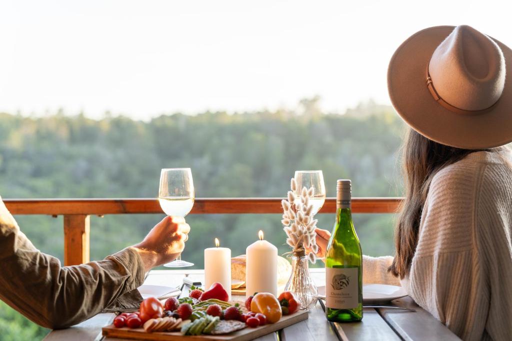 dos personas sentadas en una mesa con copas de vino en Woodlands Self Catering, en Phantom Acres