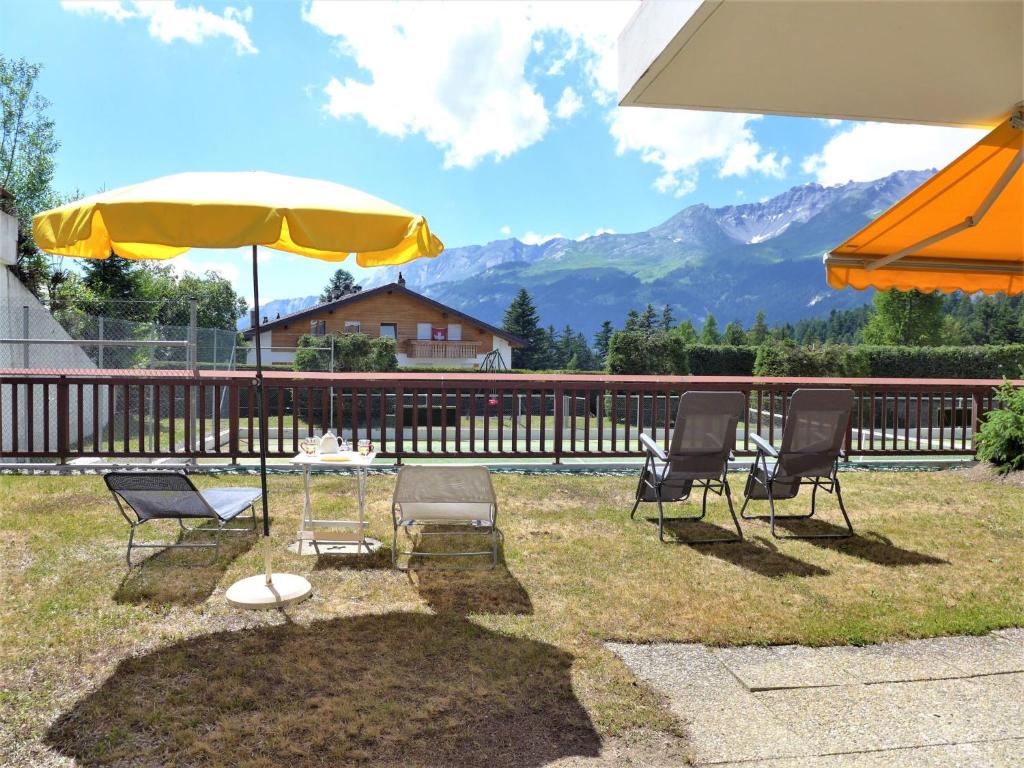 a group of chairs and a table and an umbrella at Studio Valdor by Interhome in Crans-Montana