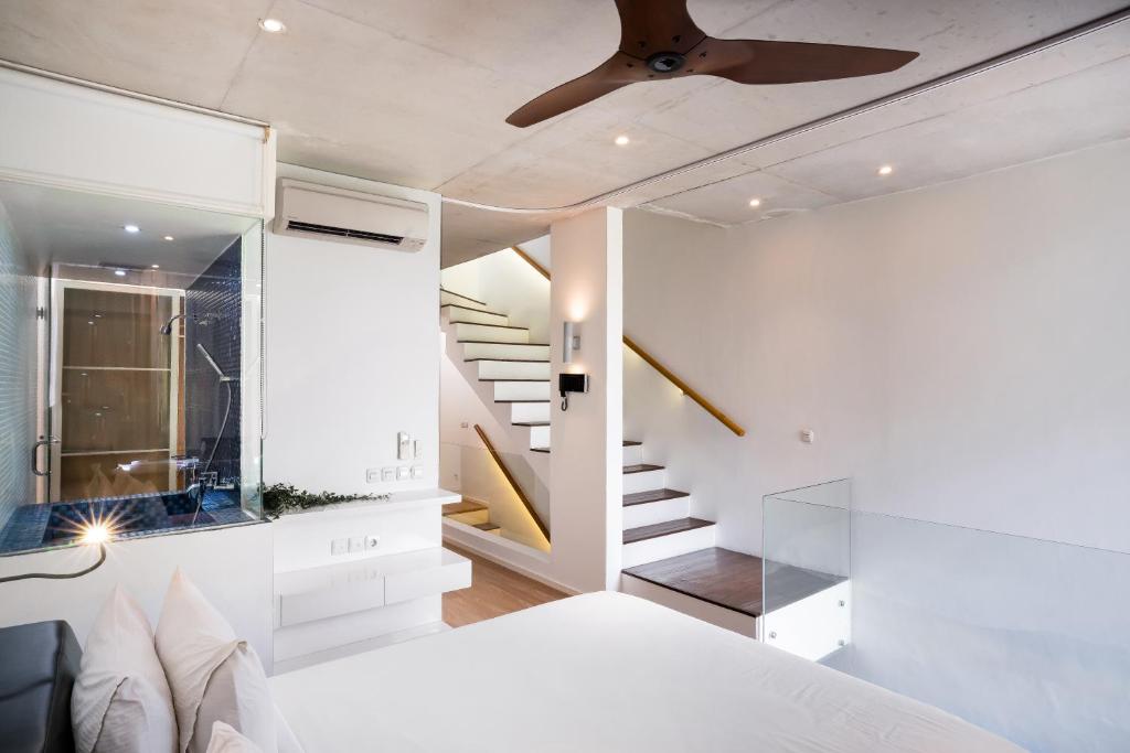 een slaapkamer met een wit bed en een trap bij Ecoloft Jababeka Golf in Cikarang