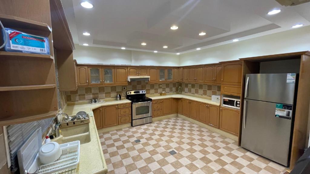 uma cozinha com armários de madeira e um frigorífico de aço inoxidável em H5-hاتش5 em Madīnat Yanbu‘ aş Şinā‘īyah