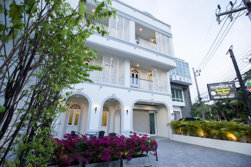 a white building with purple flowers in front of it at Number 4 in Nai Harn Beach