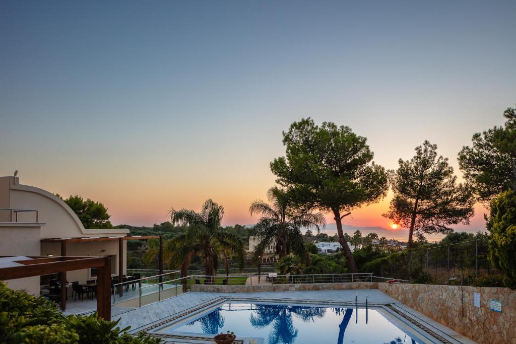 a house with a swimming pool with a sunset in the background at Angels Villa in Kambánion