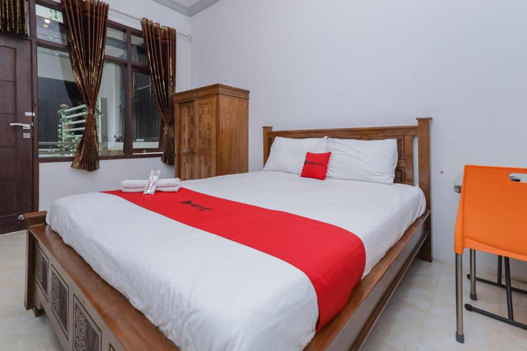 a bedroom with a large bed with a red blanket at RedDoorz At Pondok Candra in Surabaya