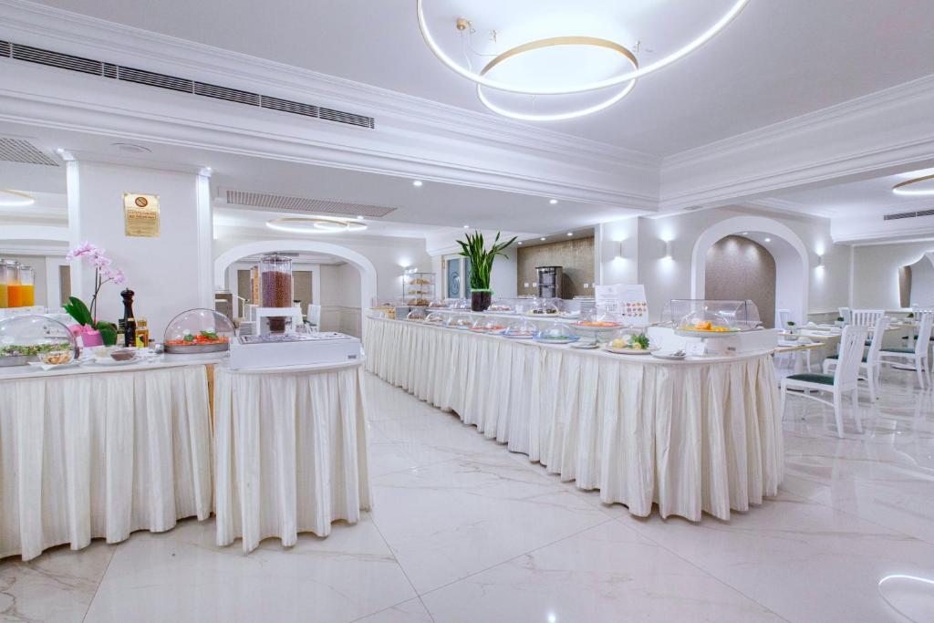 un restaurant avec des tables blanches et de la nourriture dans l'établissement Hotel Michelangelo, à Sorrente