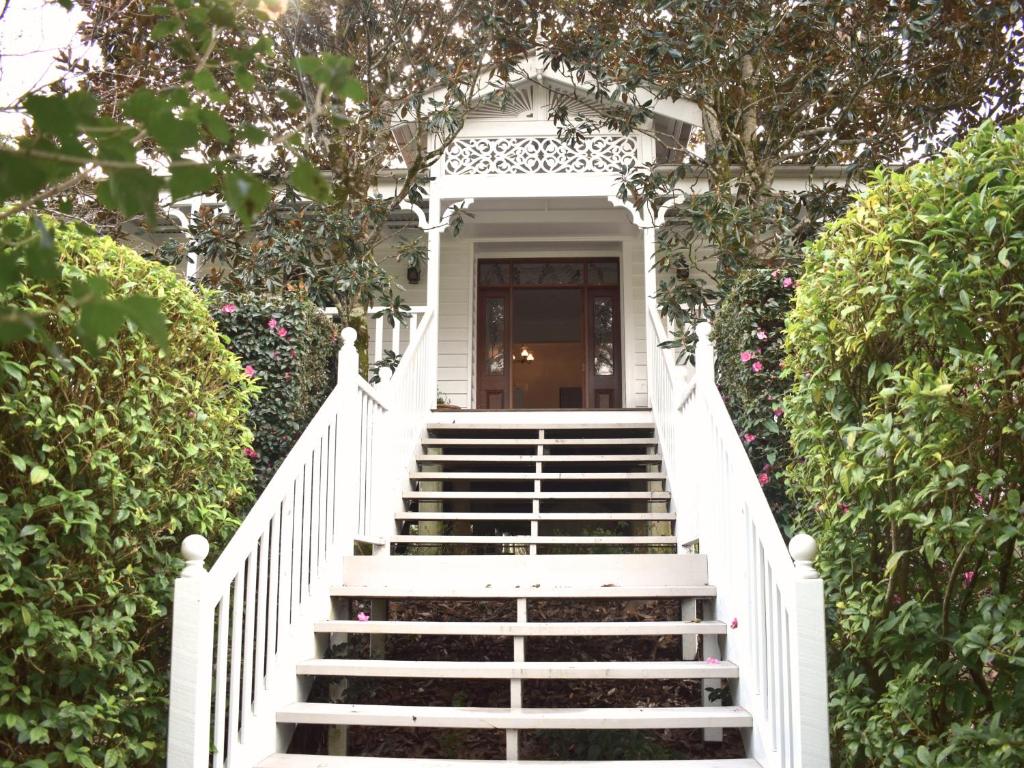 ein weißes Haus mit einer Treppe, die zu einer Tür führt in der Unterkunft Maleny Homestead & Cottage in Maleny