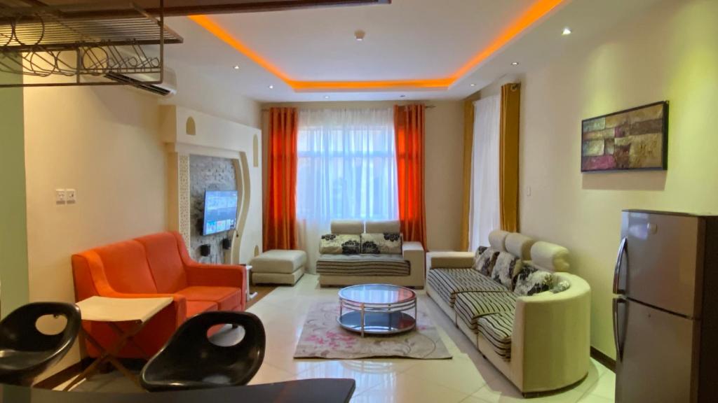 sala de estar con sillas de color naranja y sofá en Lux Suites Shanzu Seabreeze Apartments, en Shanzu