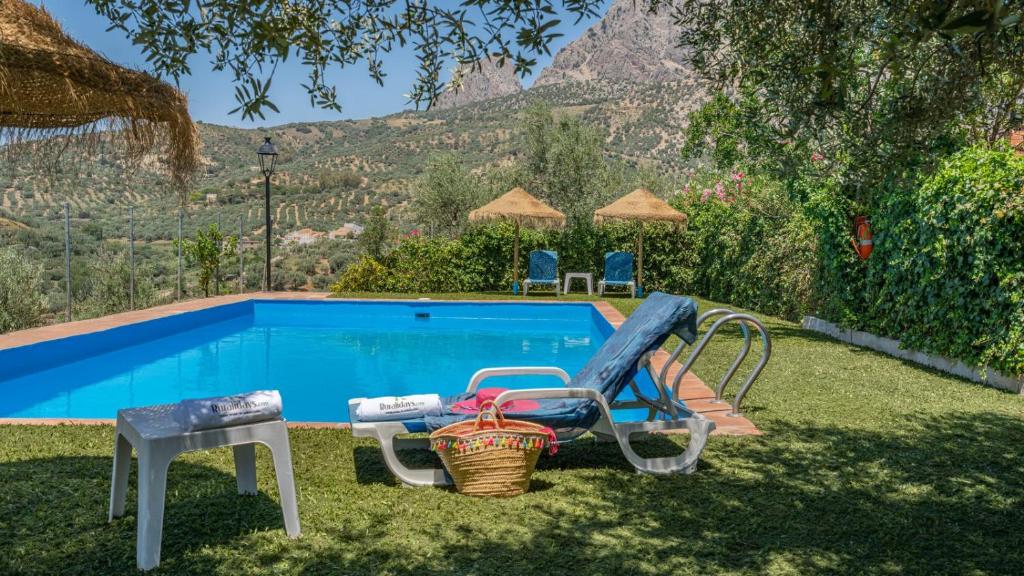 una piscina con una silla y una mesa en Casa Madrona Periana by Ruralidays, en Periana