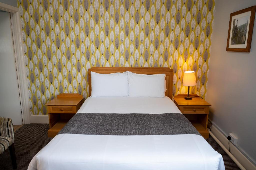 um quarto com uma cama branca e duas mesas de cabeceira em Commodore Hotel by Greene King Inns em Bournemouth