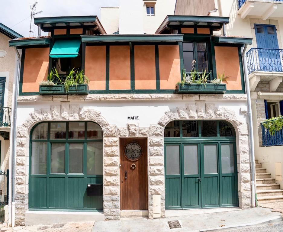 budynek z zielonymi drzwiami i oknami w obiekcie Maison MAÏTÉ, au cœur de Biarritz w Biarritz