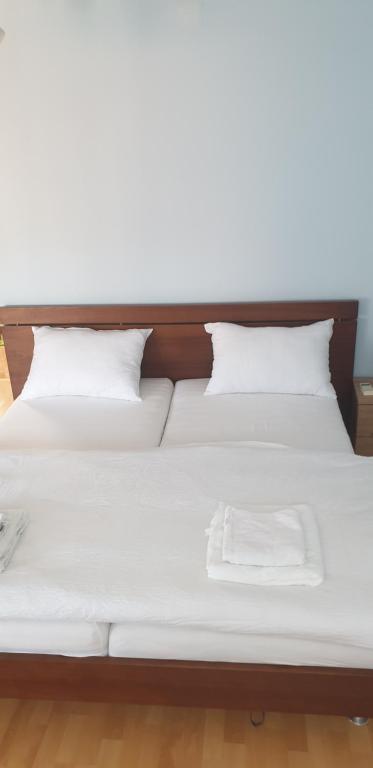 uma cama com lençóis brancos e almofadas em GIGA APARTMAN em Jagodina