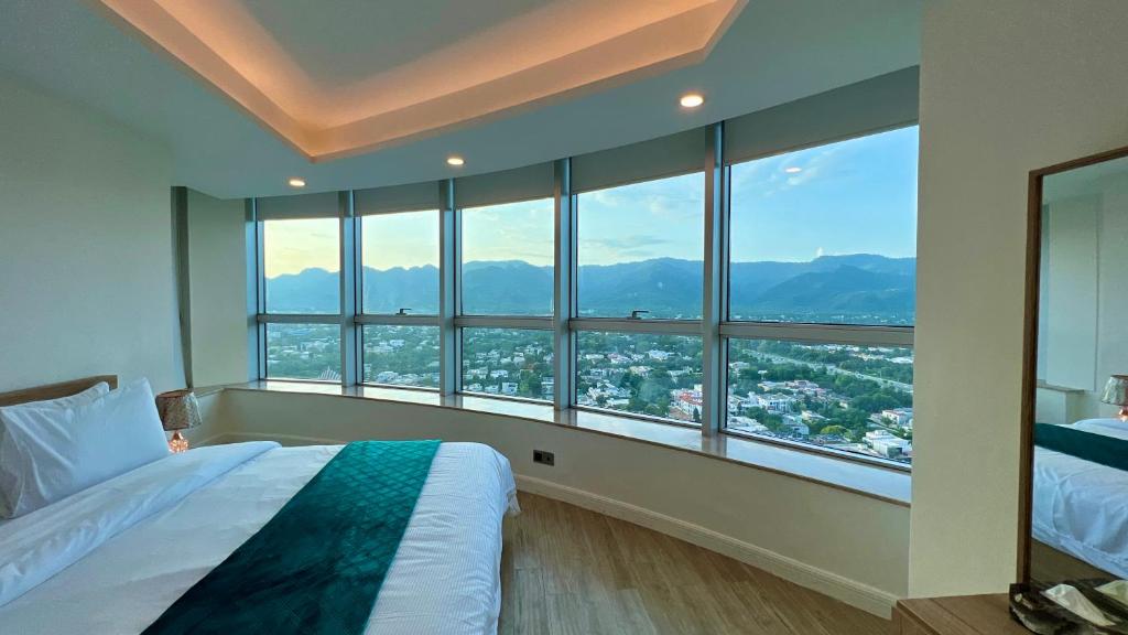 a bedroom with a large window with a view of a city at Centaurus Apartment Mountain View Two Beds in Islamabad