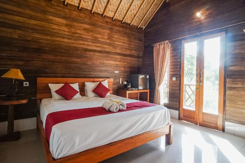 - une chambre avec un grand lit et des murs en bois dans l'établissement Penida Lapaya Bungalows Nusa Penida, à Nusa Penida