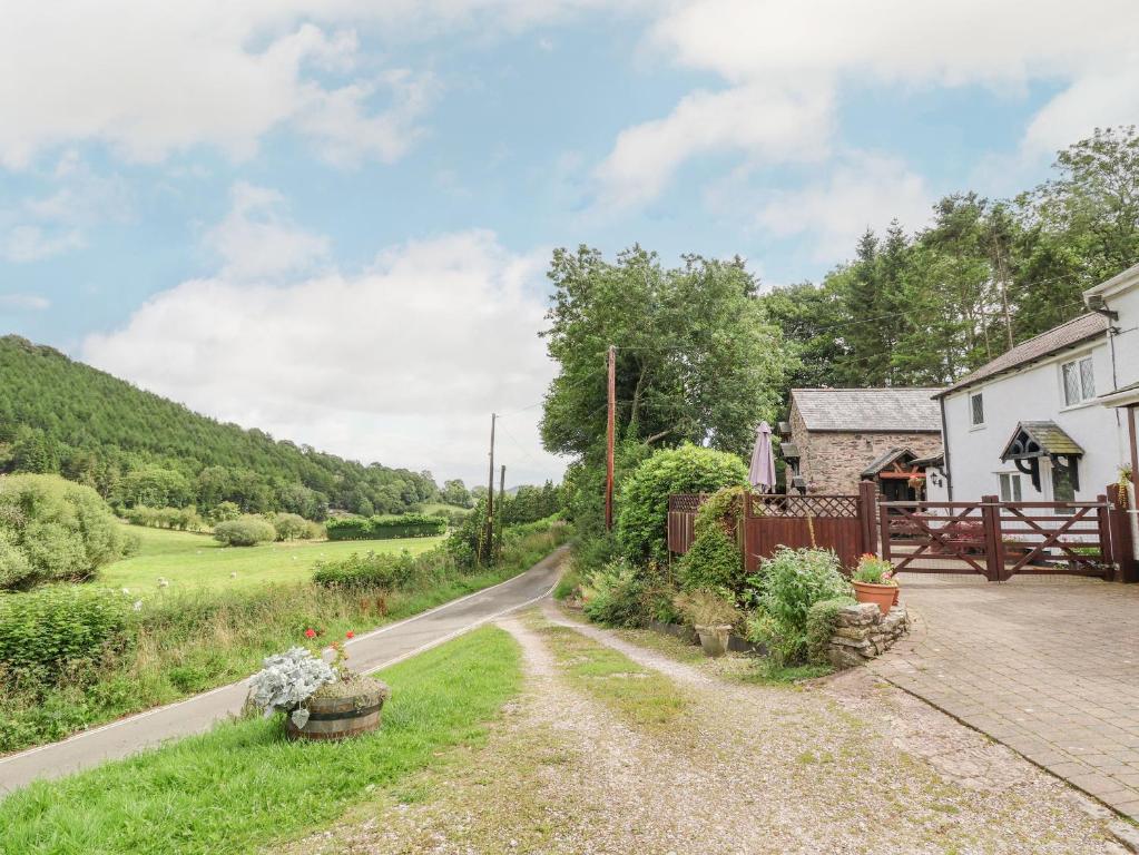 un camino que conduce a una casa blanca con una valla en The Little White Cottage, en Llanferres