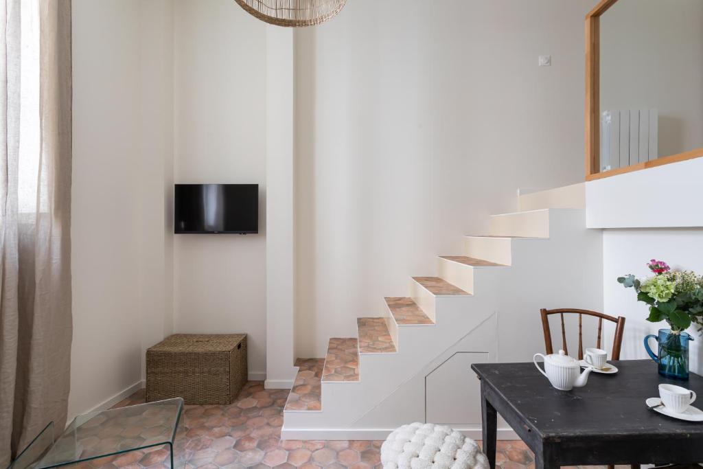- un salon avec un escalier doté d'une table et de chaises dans l'établissement L'Authentique & Le Loft Duparc - 2 Studios de charme en centre ville, à Rennes