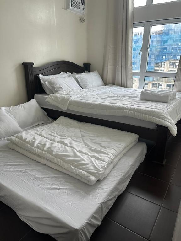 Duas camas num quarto com uma janela em The Eden’s Place At San Lorenzo em Manila