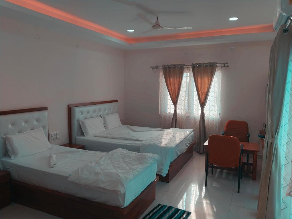 a bedroom with two beds and a chair and a table at Sambhrama Residency in Shimoga