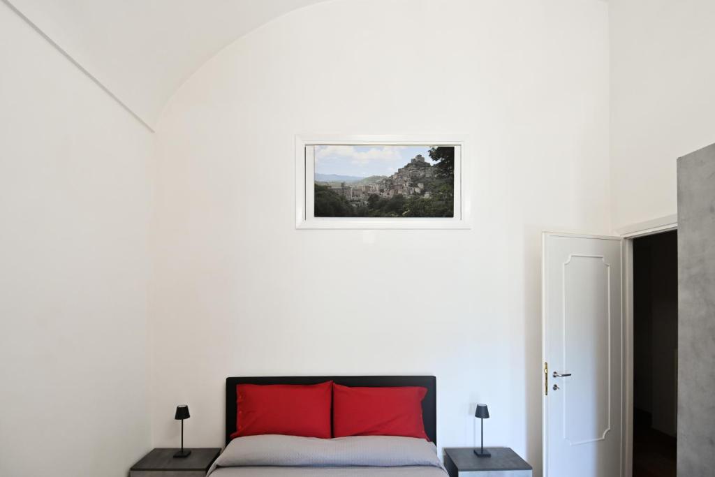 biała sypialnia z czerwonymi poduszkami na łóżku w obiekcie Residenza IL COLLE w mieście Subiaco