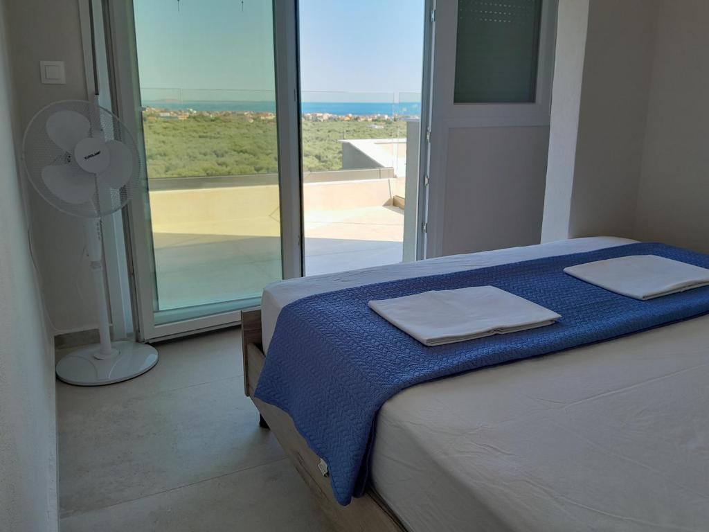 a bedroom with a bed with a fan and a window at STO LOFO Apartments Kalyvia-Limenaria Thassos in Limenaria