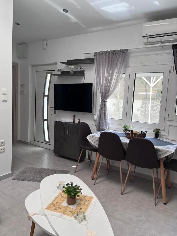 een woonkamer met een tafel en stoelen en een televisie bij Angel home in Ioannina