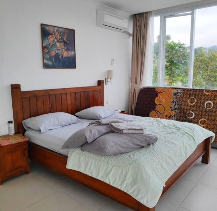 - une chambre avec un grand lit en bois et une fenêtre dans l'établissement Homstay harian pak.anwar, à Bogor