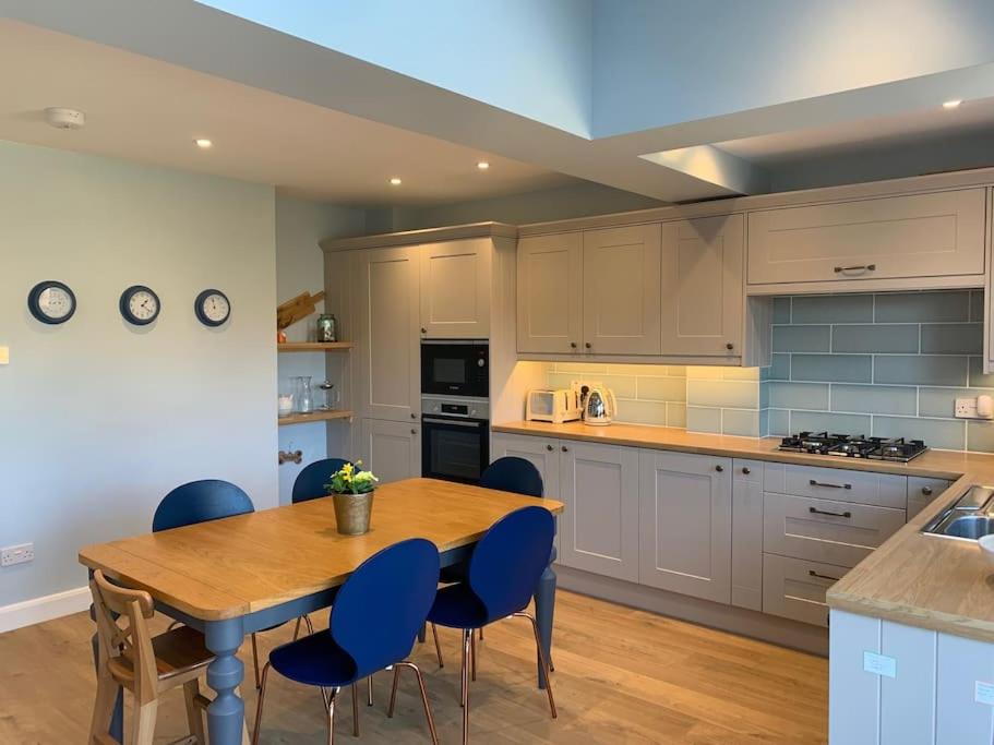a kitchen with a wooden table and blue chairs at Nina's Cottage - Southwold in Southwold