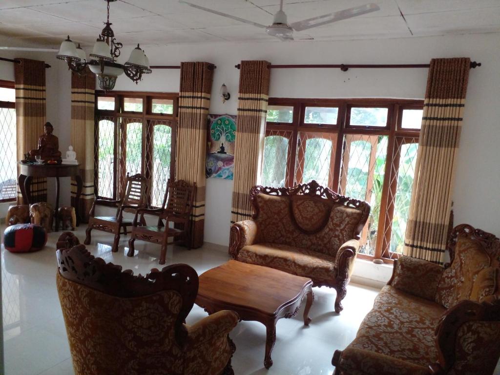 a living room with chairs and tables and windows at Muthu Villa in Kalutara