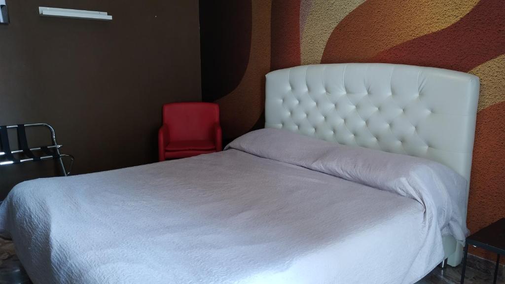 sypialnia z białym łóżkiem i czerwonym krzesłem w obiekcie CconfortHotels R&B Semplici Emozioni - SELF CHECK IN w mieście Bari