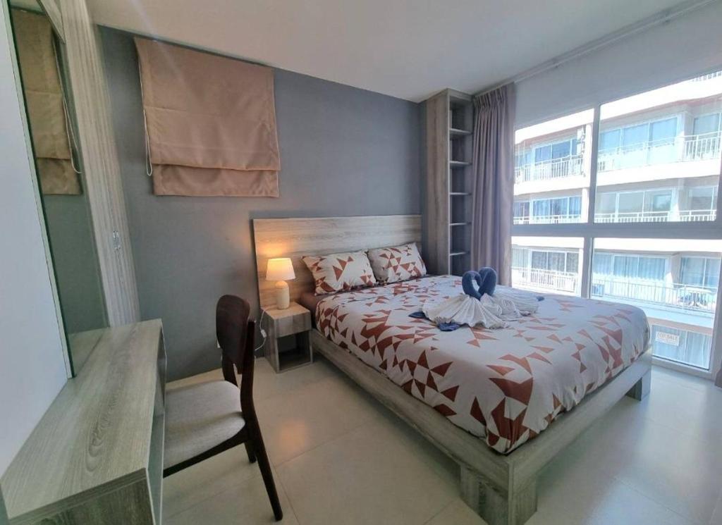 a bedroom with a bed and a chair and a window at Grandblue condominium 301 in Ban Tha Fat