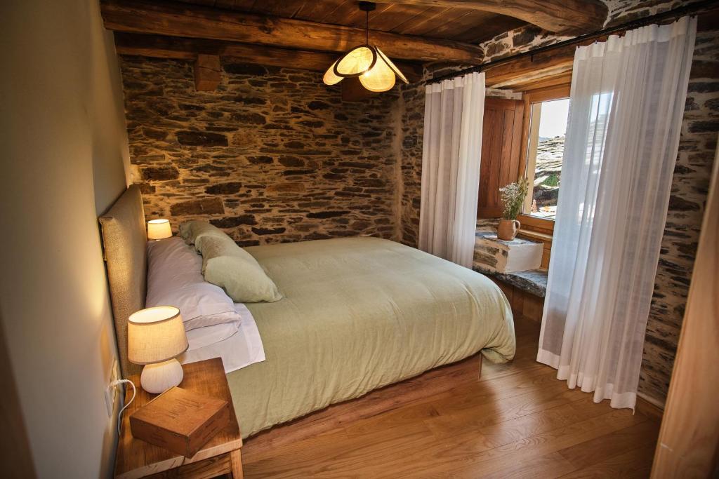 um quarto com uma cama e uma parede de tijolos em Lar da cima em Folgoso