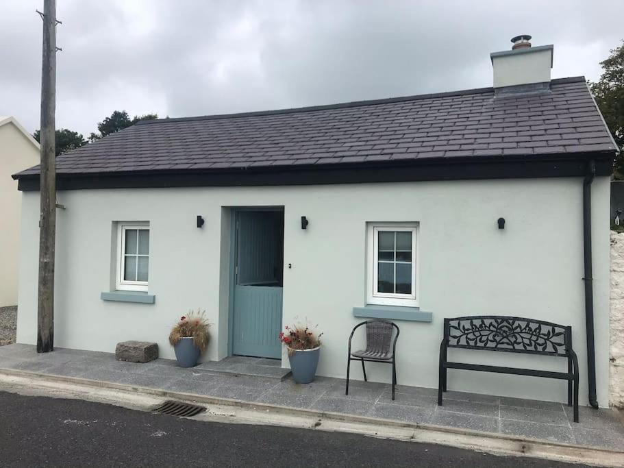 a white house with a bench in front of it at 3 Quay Cottage Killala. Luxury Sea-Front Cottage in Killala