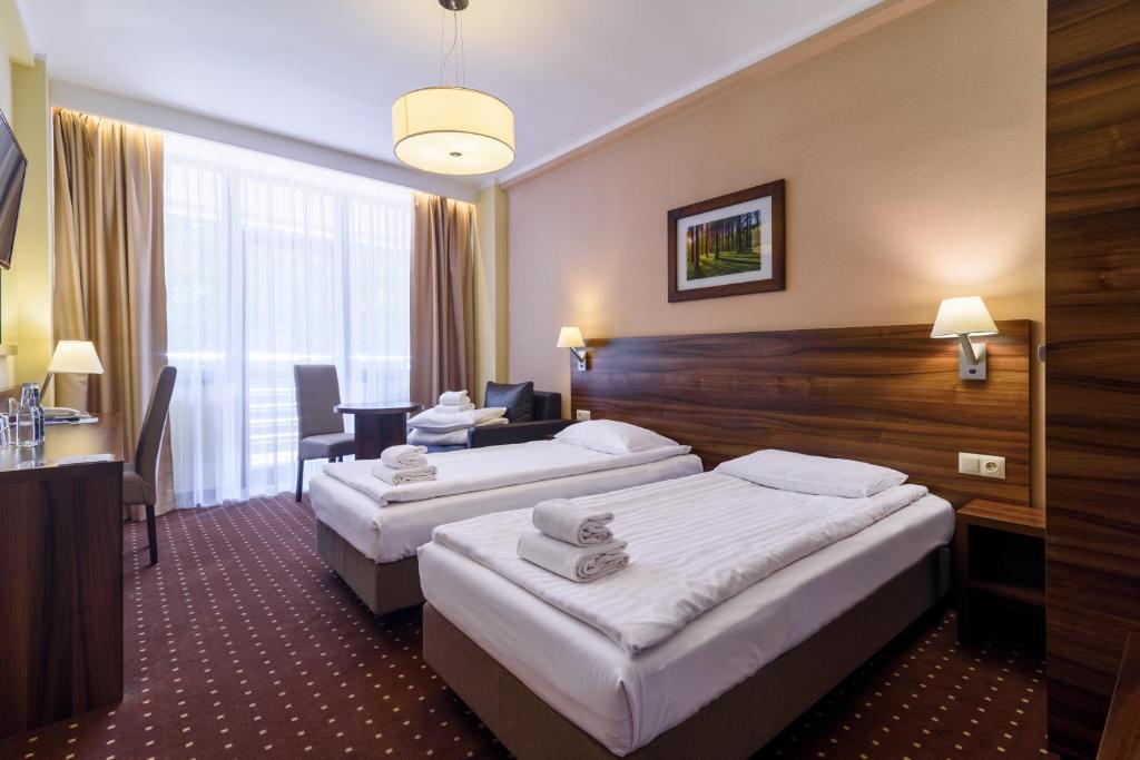 a hotel room with two beds and a desk at Hotel Podium in Wisła