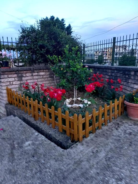 a garden with red flowers in a wooden fence at GuestHouseMantho in Gjirokastër