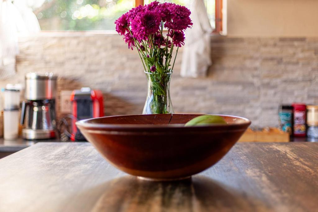 a wooden bowl with a vase with purple flowers in it at El Sali Guest House in Hilton