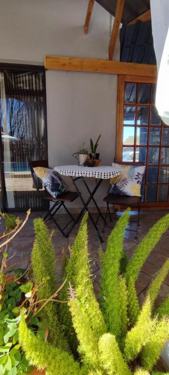 un patio con mesa, sillas y plantas en Be My Guest, en Alberton