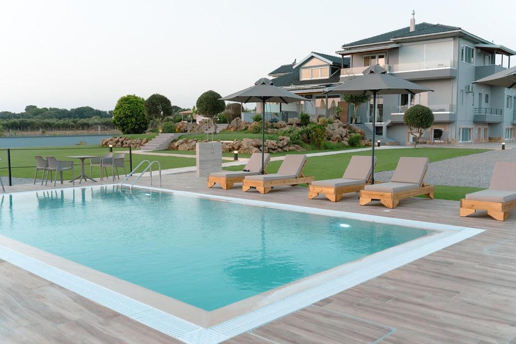 a swimming pool with chairs and a table and a house at ALS COMFORT SUITES in Preveza