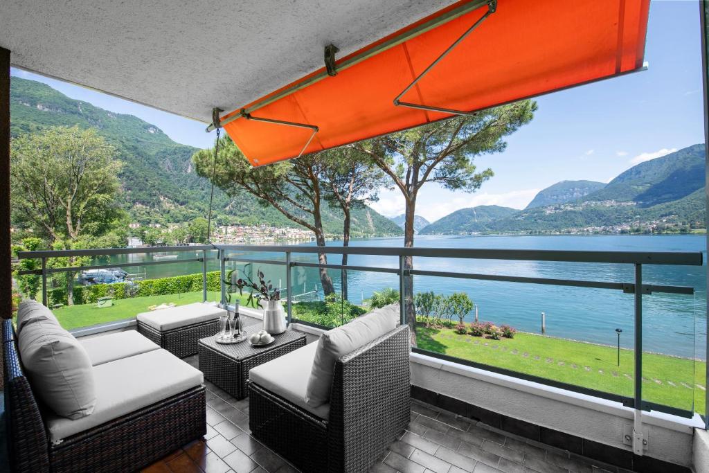 een patio met uitzicht op het water en de bergen bij Emotion Lake View - Happy Rentals in Capolago