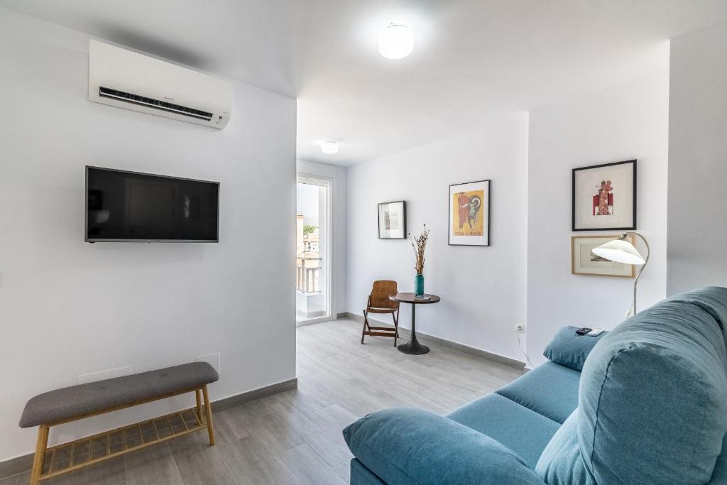 salon z niebieską kanapą i telewizorem w obiekcie Livemálaga Victoria Suites w Maladze