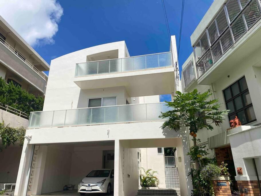 ein weißes Haus mit einem Balkon und einem Auto in der Unterkunft Vacation Rental Kally Naha Okinawa in Naha